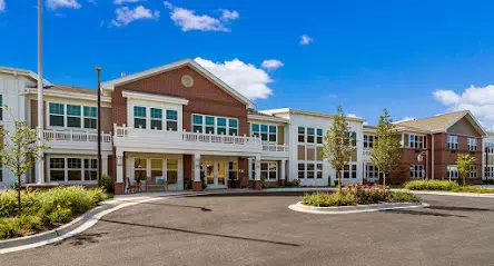 Exterior view of Franklin Place memory care community in Franklin, WI, featuring a welcoming entrance, landscaped surroundings, and a clear blue sky.