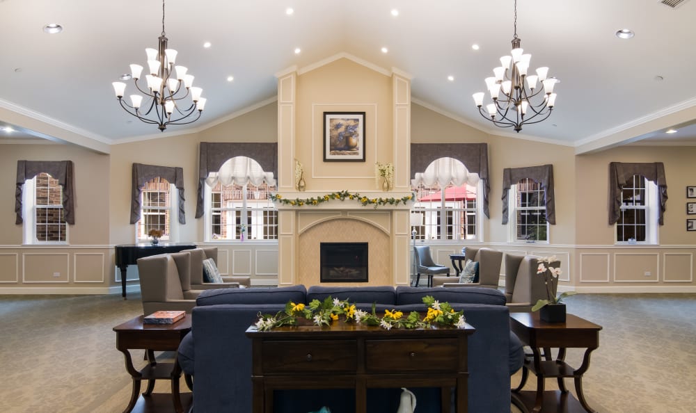 Welcoming lobby of Churchill Place at Anthem Memory Care in Glen Ellyn, IL, featuring elegant chandeliers, comfortable seating, and decorative floral arrangements.