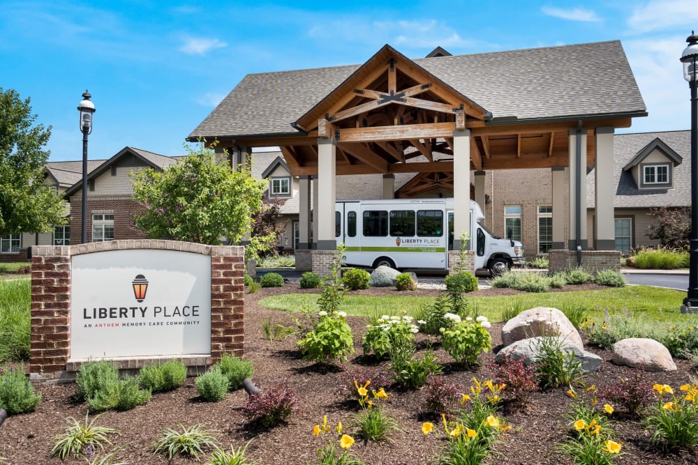 Liberty Place memory care community entrance in West Chester, OH, featuring landscaped gardens, a welcoming sign, and transportation vehicle.