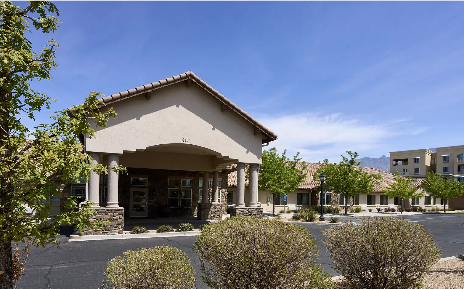 North Ridge Memory Care community entrance in Albuquerque, NM, featuring a welcoming facade, landscaped surroundings, and clear blue sky, highlighting the supportive environment for seniors.