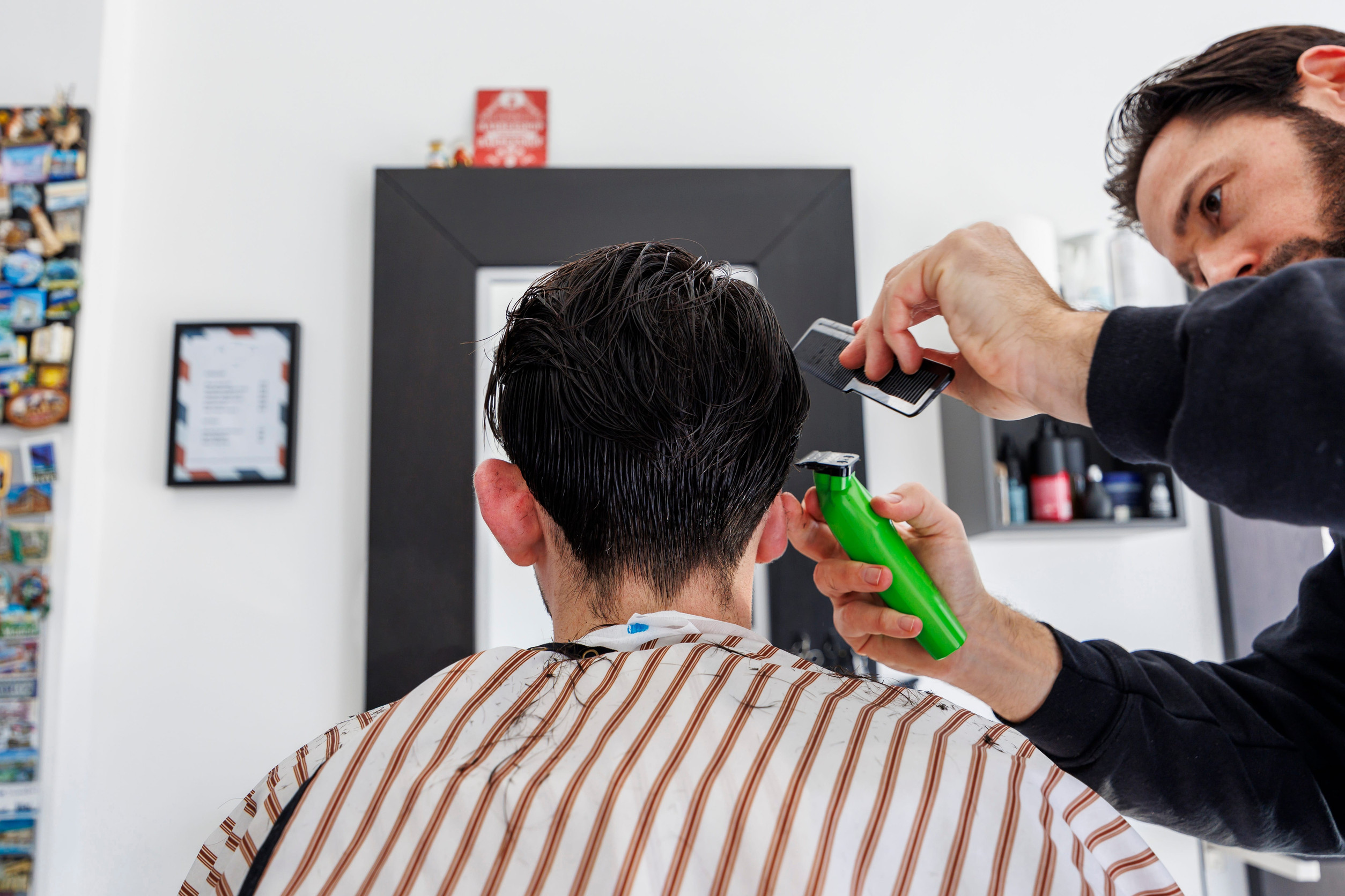 Un hair stylist che segue le istruzioni per il taglio fornite da un uomo che ha fatto un trapianto di capelli
