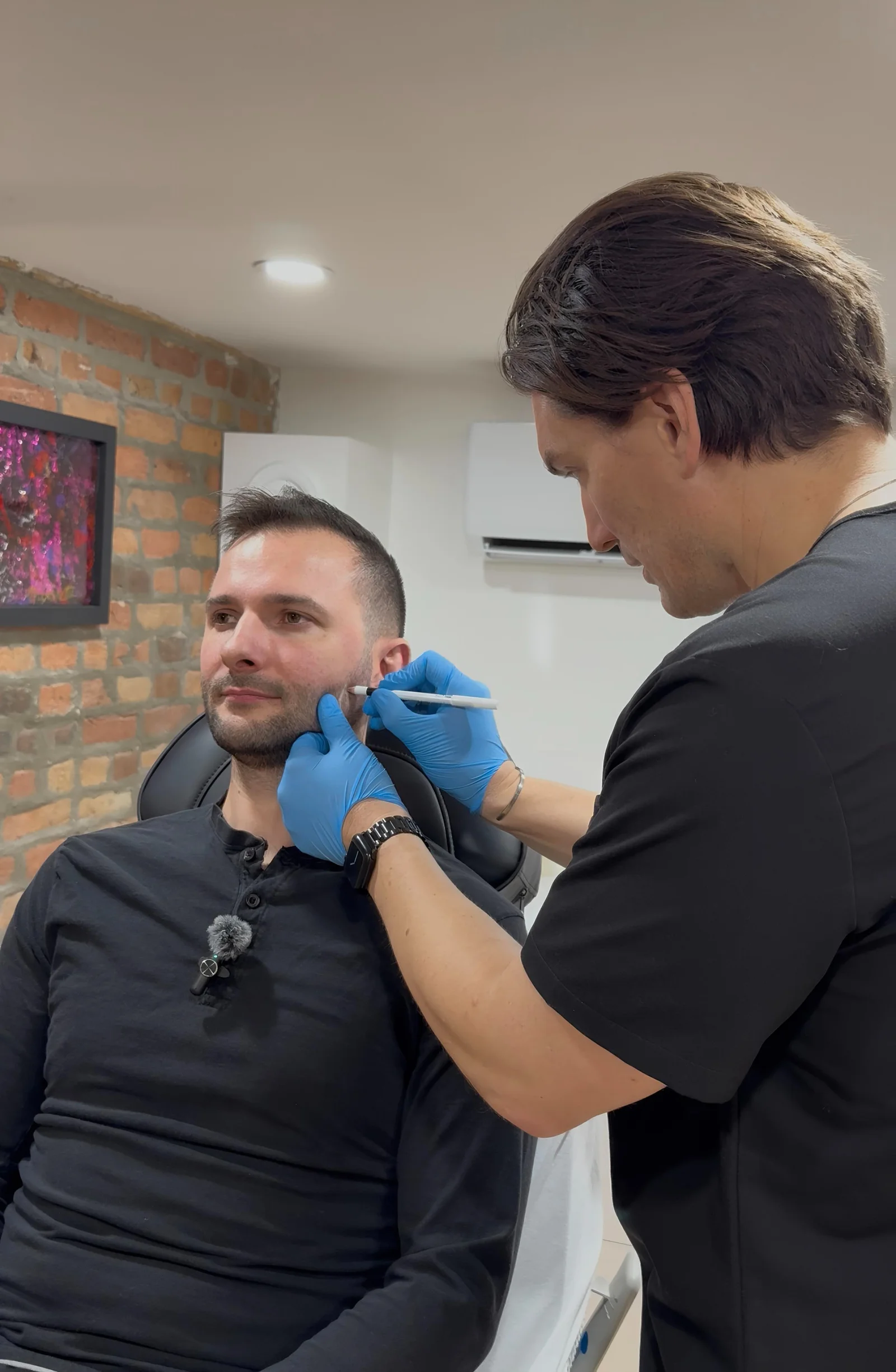 Médecin marquant les points d'injection sur le visage d'un patient avant un affinement de la mâchoire