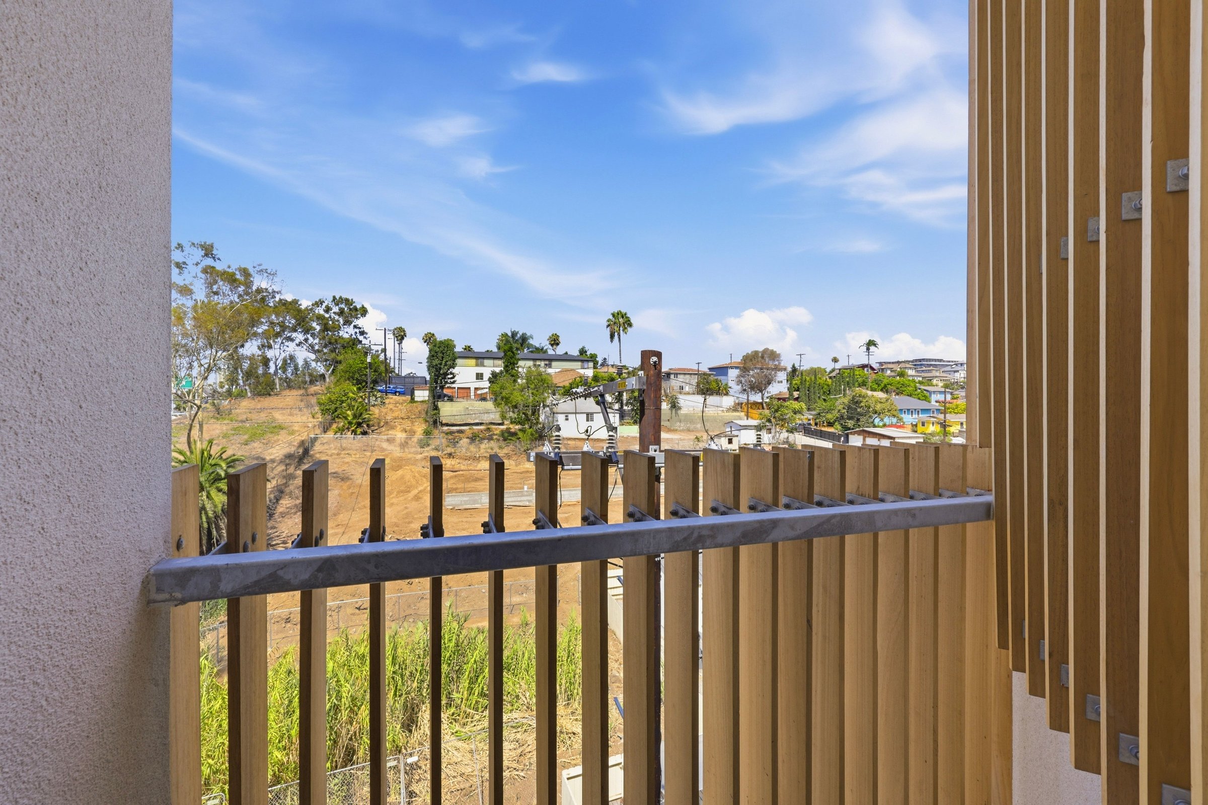 Private Goldilocks apartment balcony with wood privacy slats and neighborhood views.