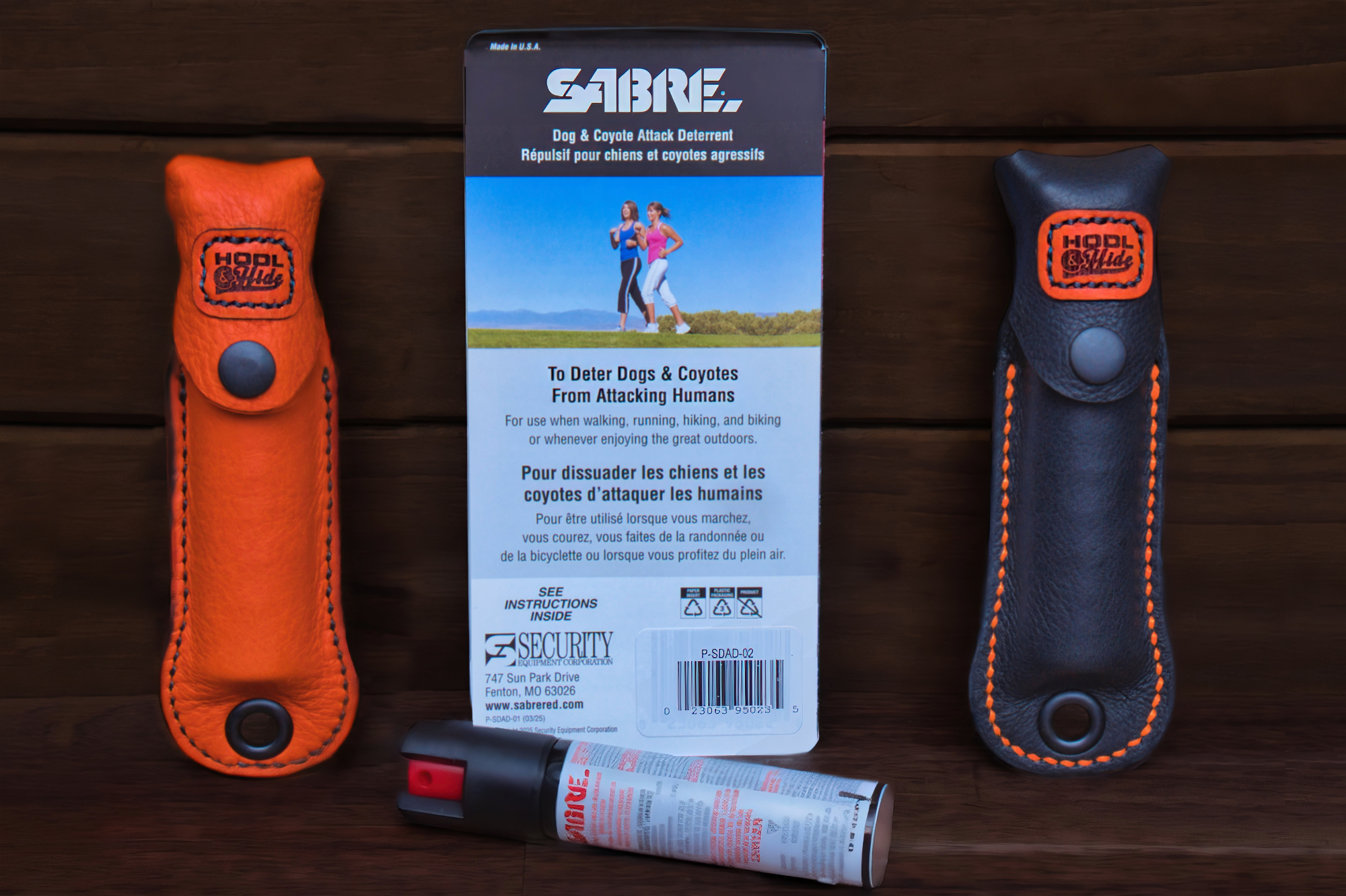Sabre dog and coyote attack deterrent spray with orange and black holsters on a wooden surface.