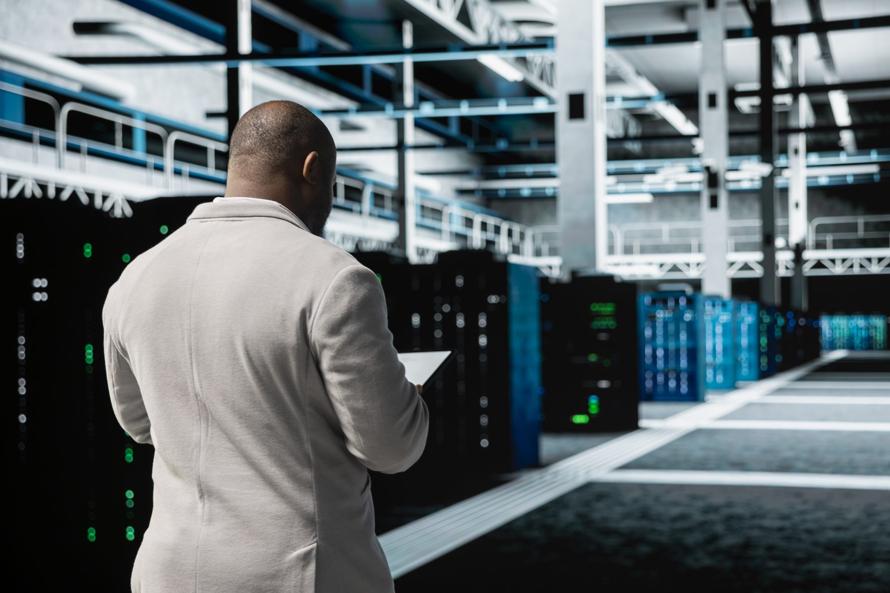 A technician checking a tablet beside rows of servers in a data center