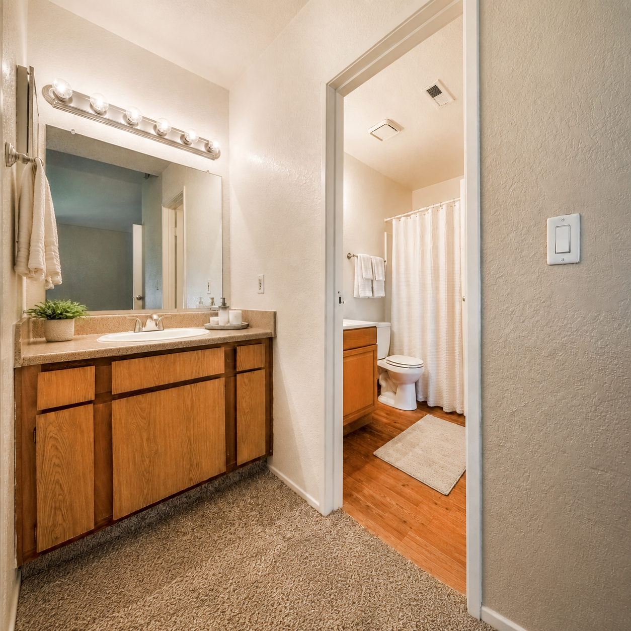 Bathroom with shower tub combo and vanity area with brown cabinets
