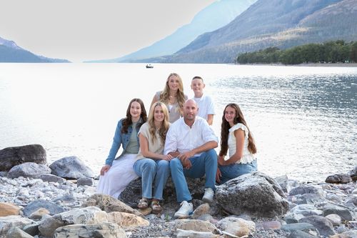 Jeff Hill and his family sitting on the rocky shore of Waterton Lakes, Alberta