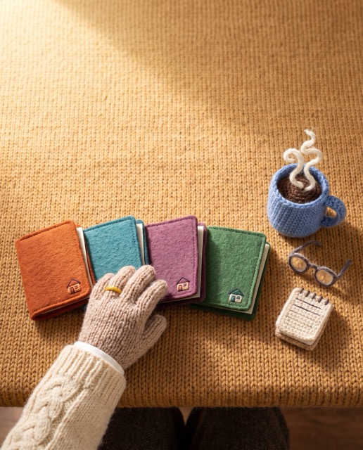 A knitted hand choosing between four small folders on a table