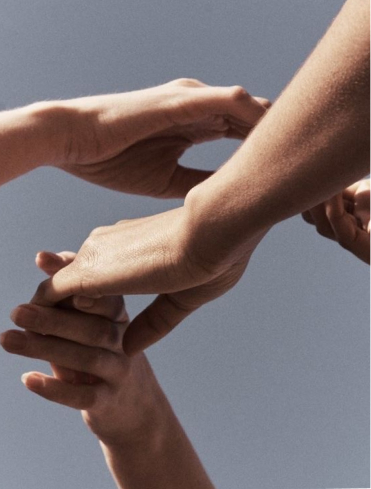 Two people holding hands in a gesture of support, comfort, and human connection