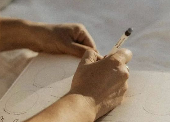 Person writing in a journal or notebook, engaged in reflective self-expression
