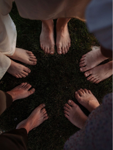 Person kneeling and touching fresh green grass, symbolising grounding and connection with nature