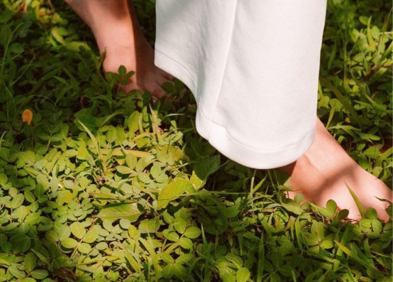 Person crouching down and touching green grass with their hands in an open field
