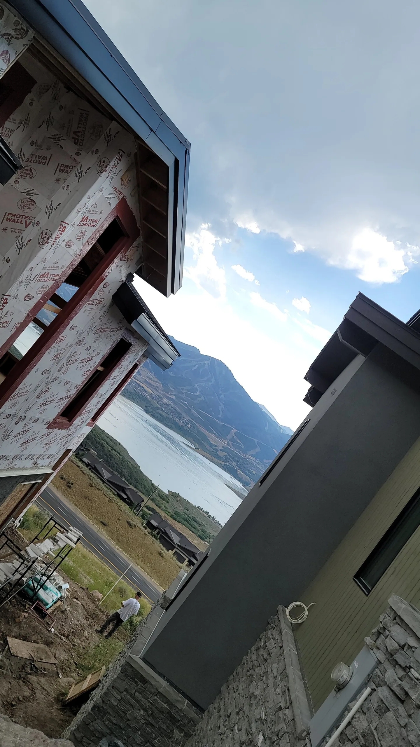 Mountain and lake view between two modern house at job site with the owner by the road.