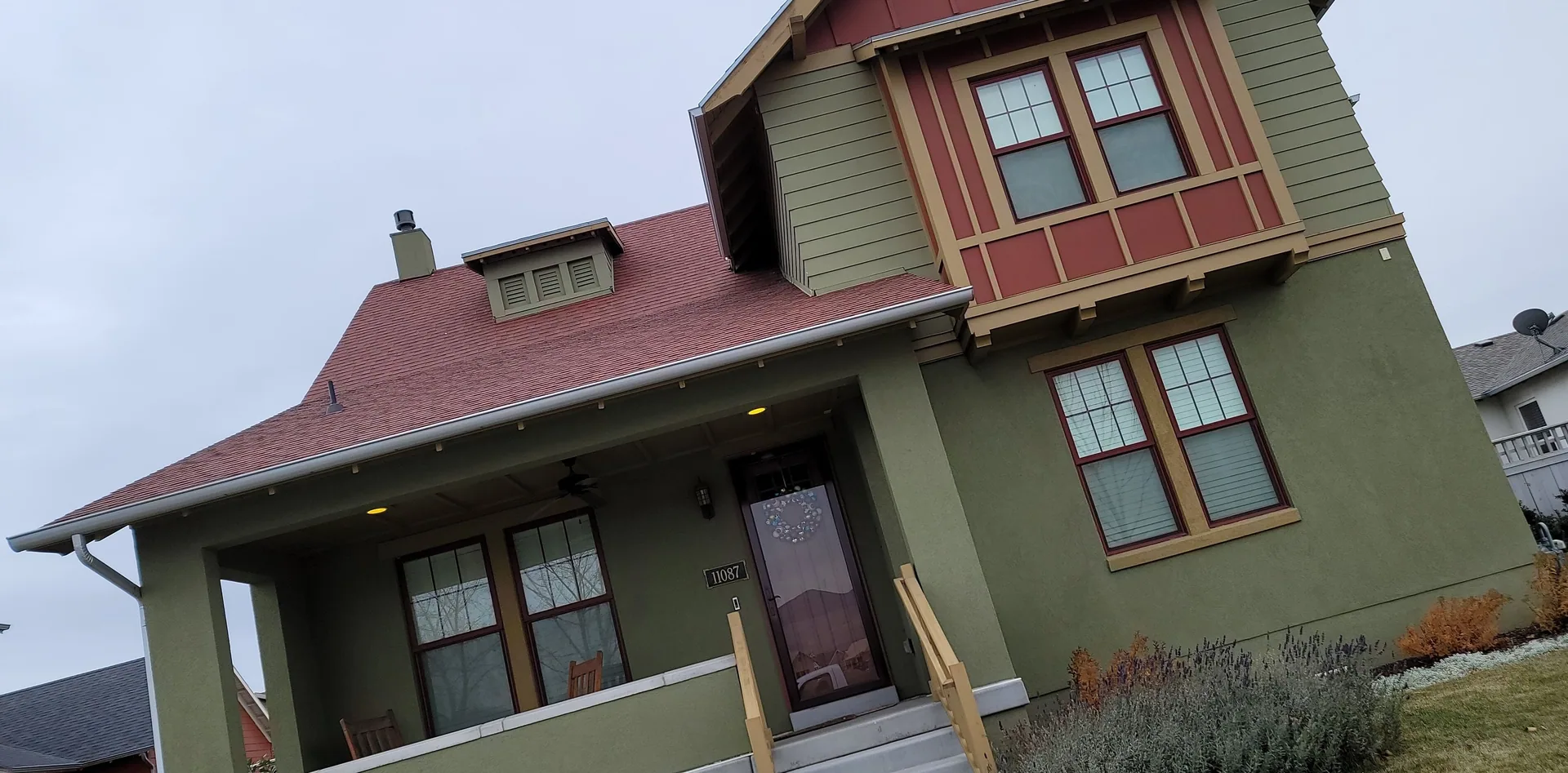 Green stucco house with red roof, front porch.