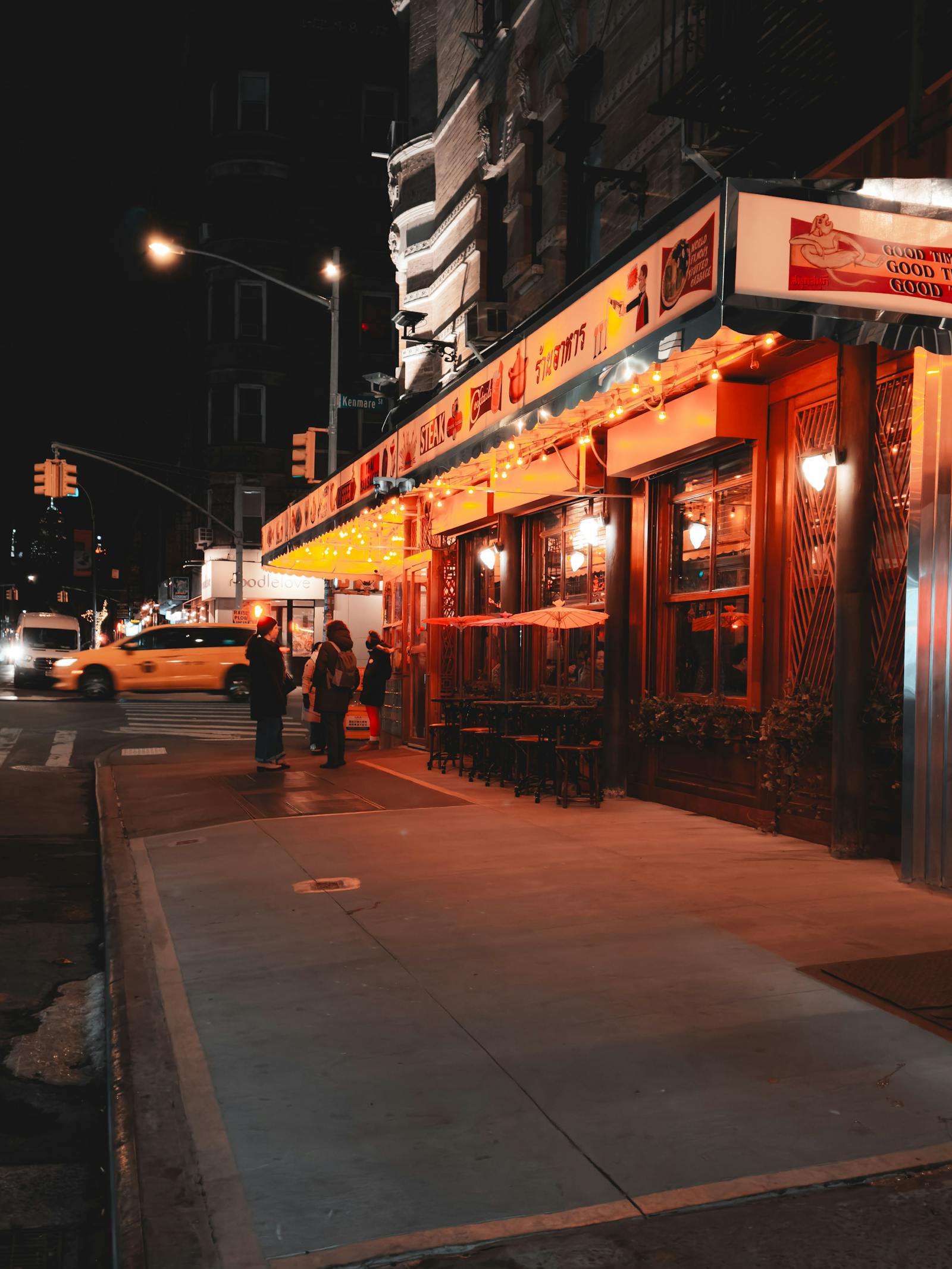 Nighttime cityscape of a lively New York City street with a glowing restaurant and a classic yellow taxi. Photo by Allen Boguslavsky on Pexels.