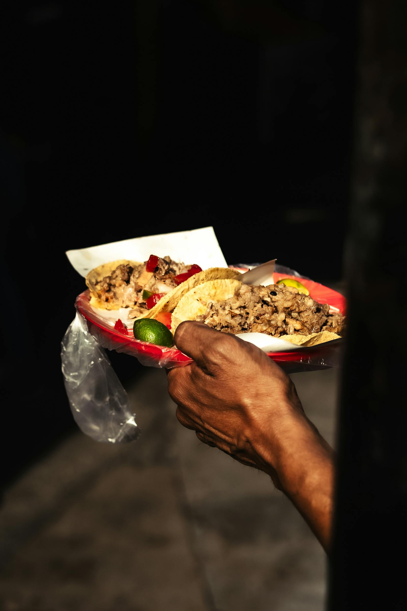 A hand holding a plate of authentic Mexican street tacos in Mexico City. Photo by Joyboy on Pexels.