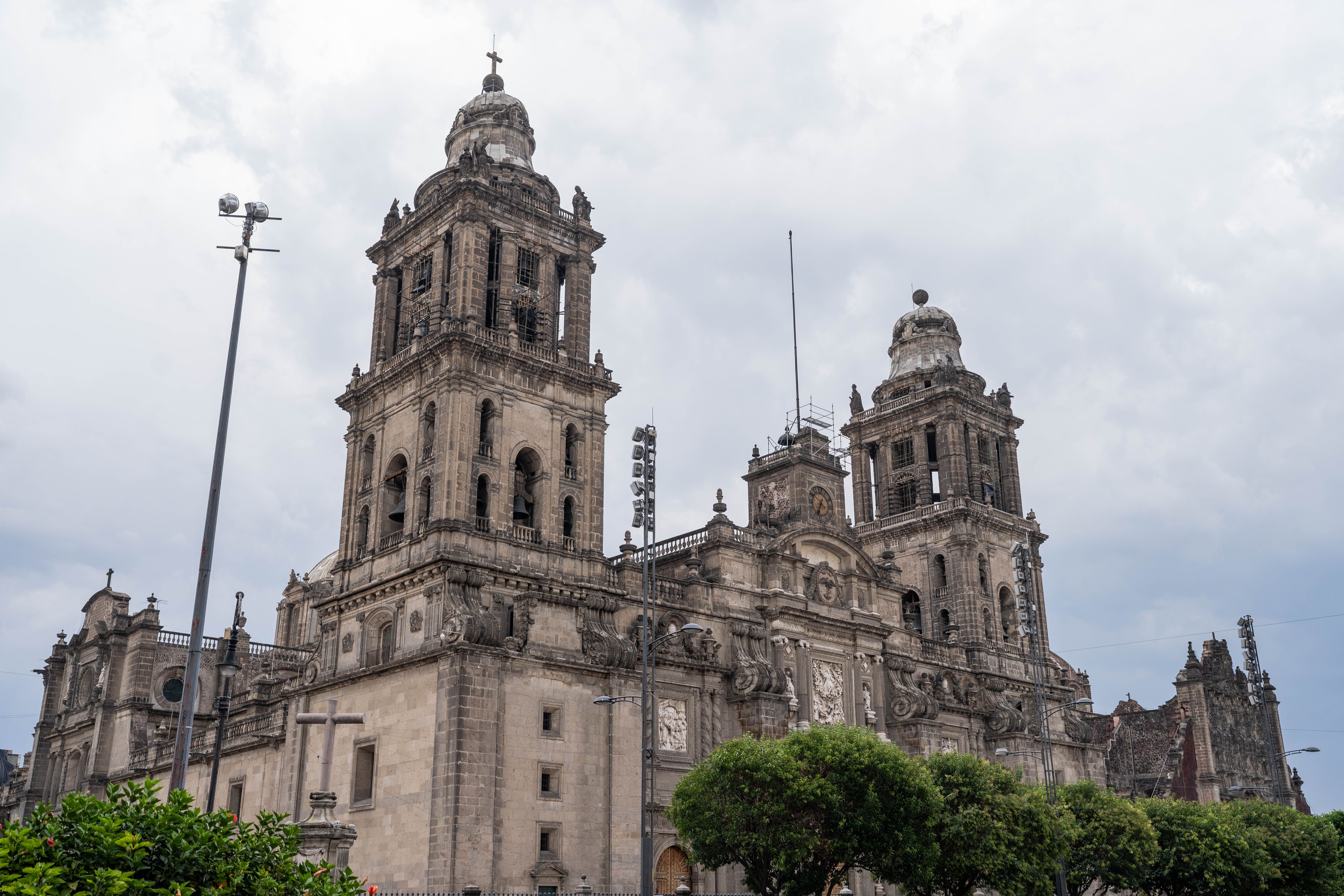 The stone bell towers of the Metropolitan Cathedral rise over the trees at the edge of the Zocalo in Mexico City. Photo by Amar Preciado on Pexels.