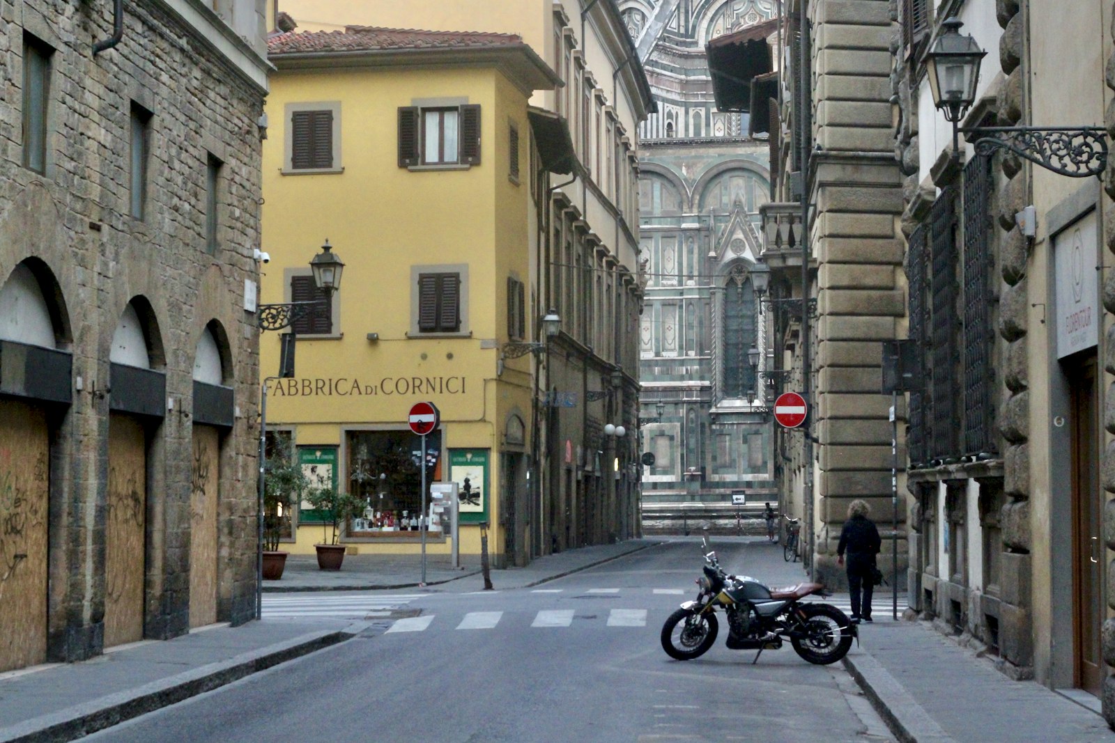 A nearly empty Florence street at dawn, the Duomo's marble flank glowing at the end of it. Photo by David Tip on Unsplash.