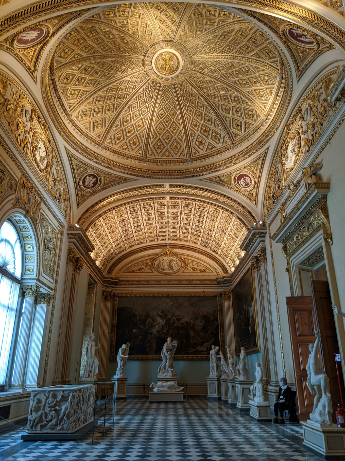 A gilded sculpture room at the Uffizi, classical statues lining the walls. Photo by Tzenik on Unsplash.