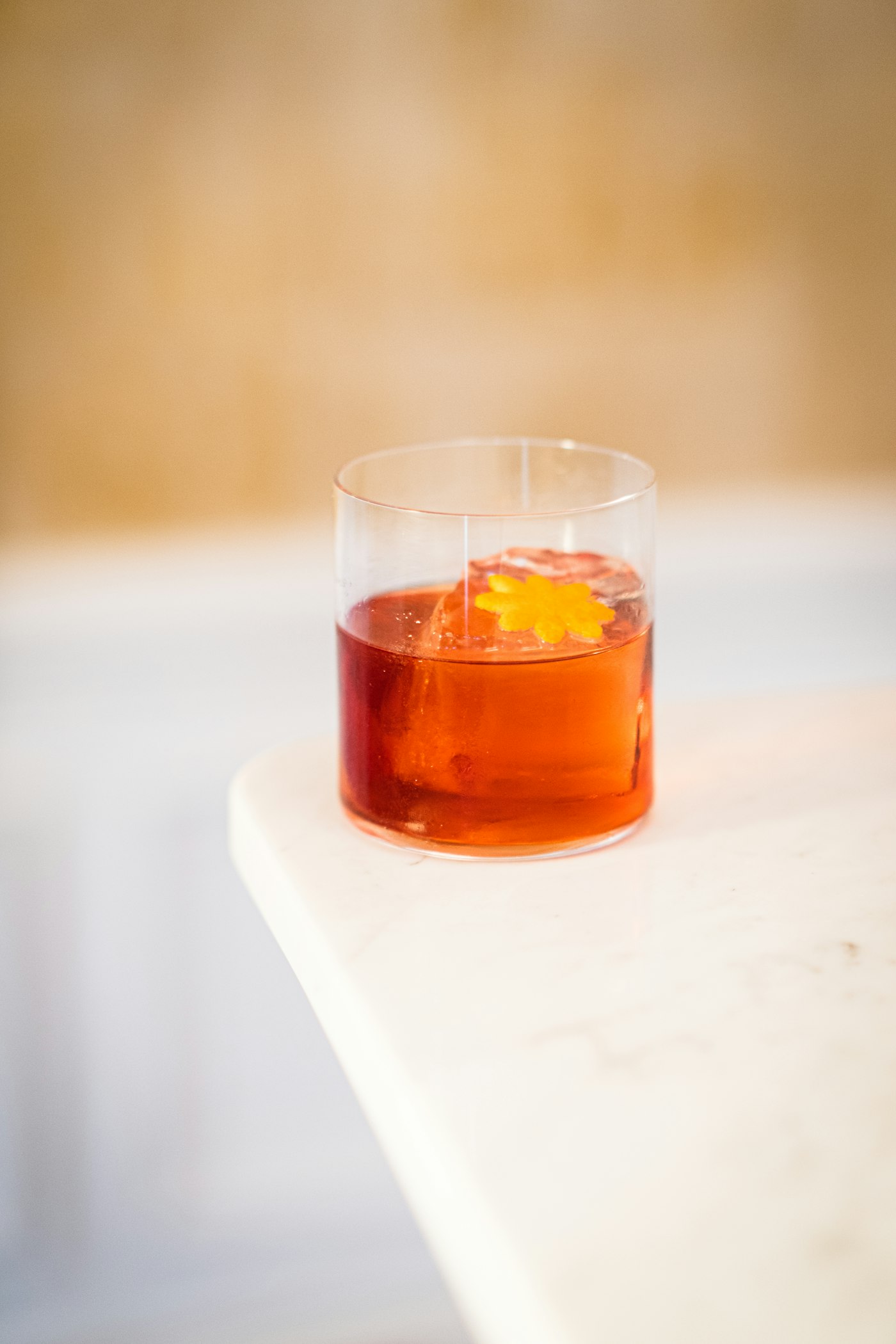A Negroni with an orange twist on a marble bar top. Photo by Timothé Durand on Unsplash.