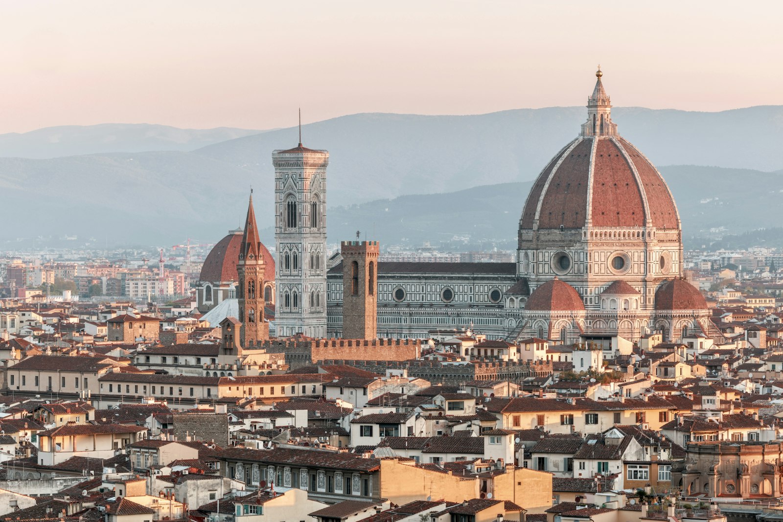 Florence skyline at sunrise — Brunelleschi's dome and Giotto's campanile rising above the terracotta rooftops. Photo by Henrique Ferreira on Unsplash.