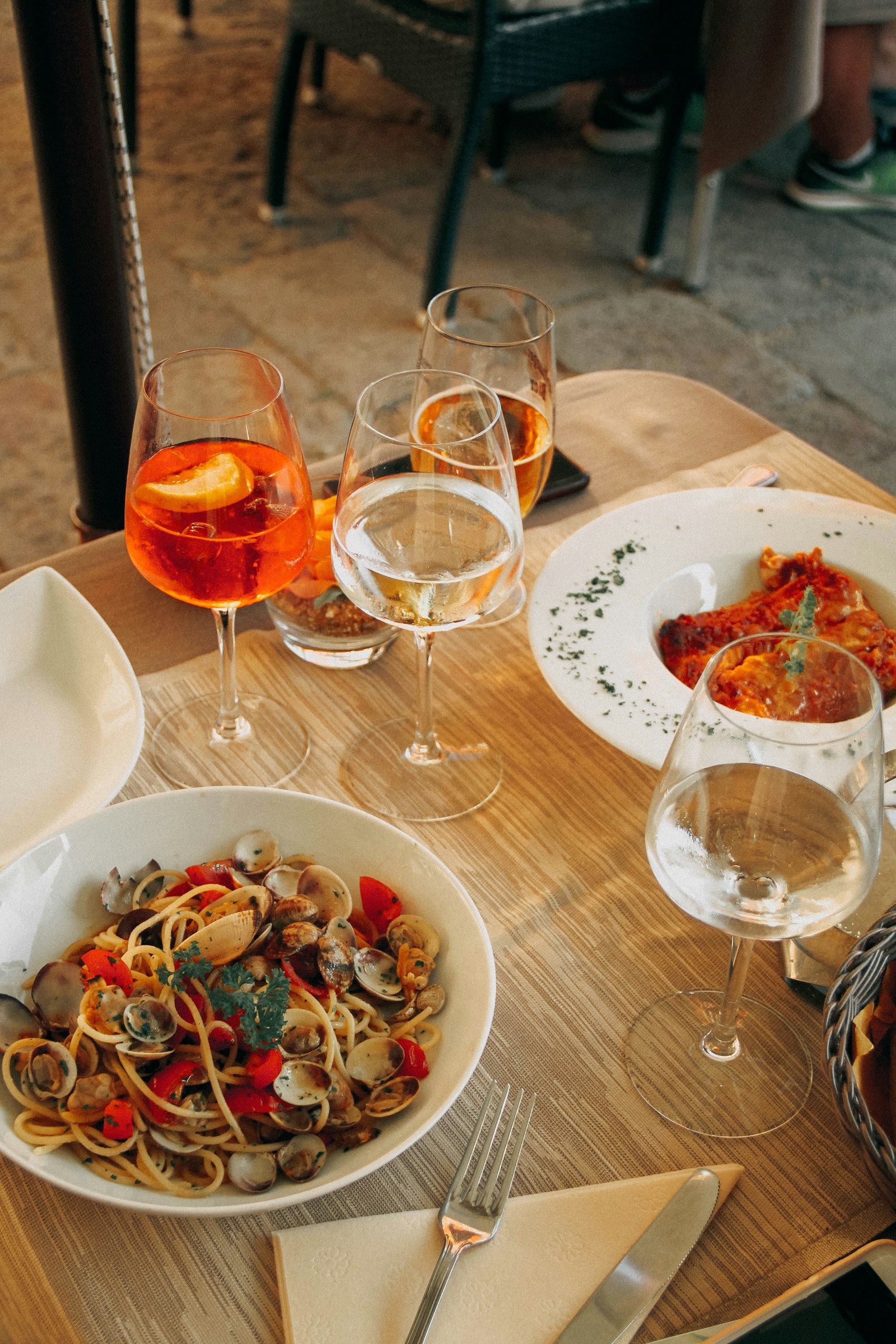 Spritz, white wine, and plates of pasta on a Venetian table. Photo by Liubov Ilchuk on Unsplash.