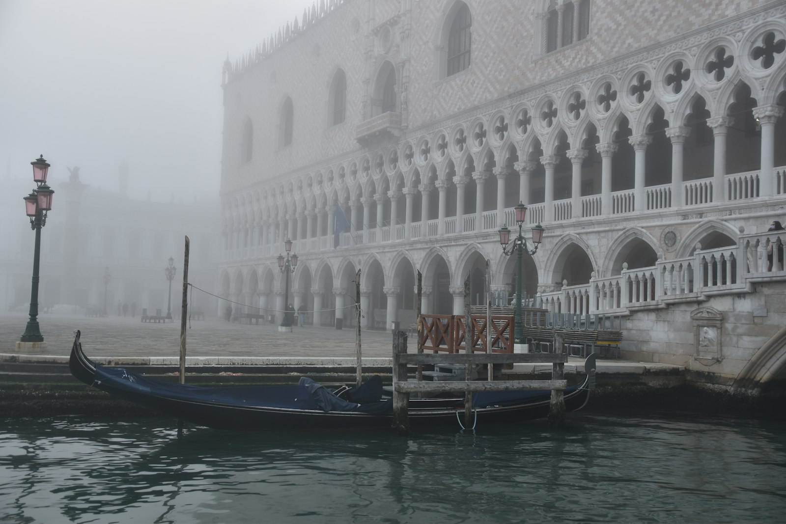 A gondola gliding past the Doge's Palace in morning fog. Photo by Micky White on Unsplash.