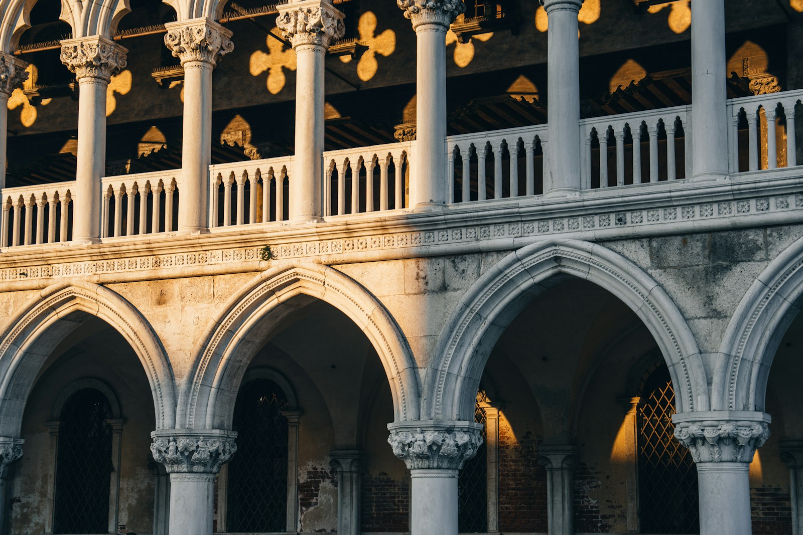 Arches and columns of a Venetian palace arcade in warm light. Photo by Peter Thomas on Unsplash.