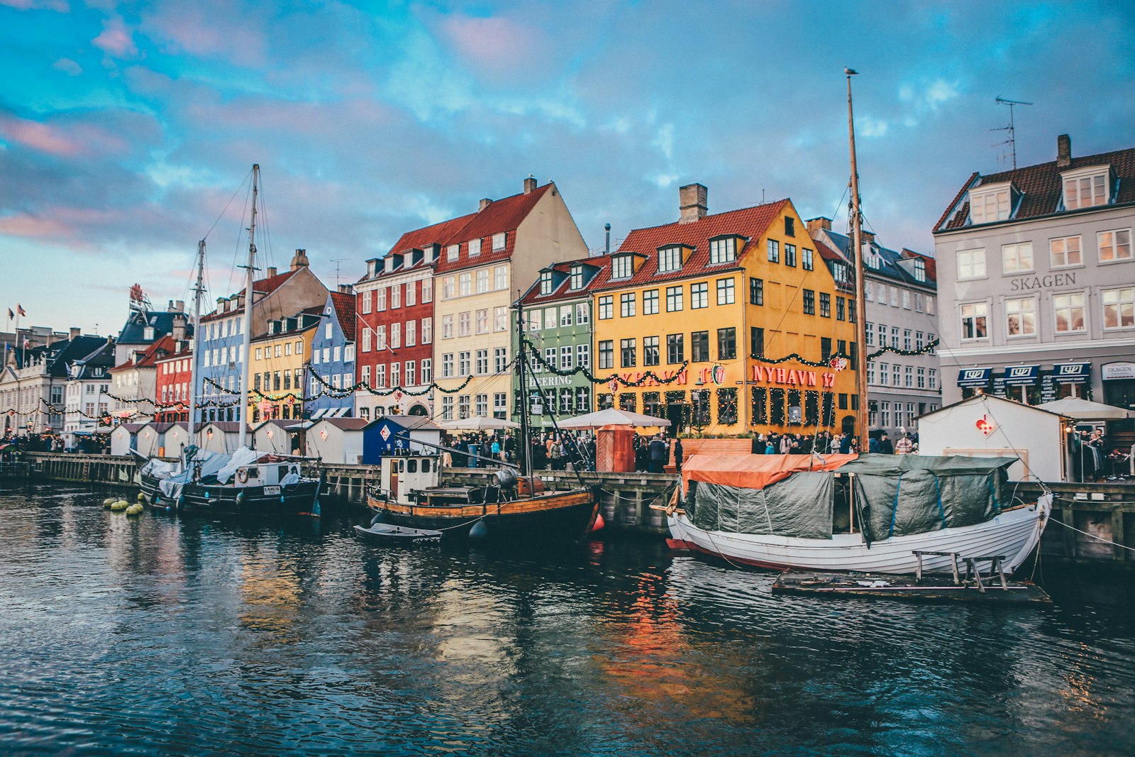 Nyhavn's colored townhouses and moored wooden boats at dusk. Photo by Nick Karvounis on Unsplash.