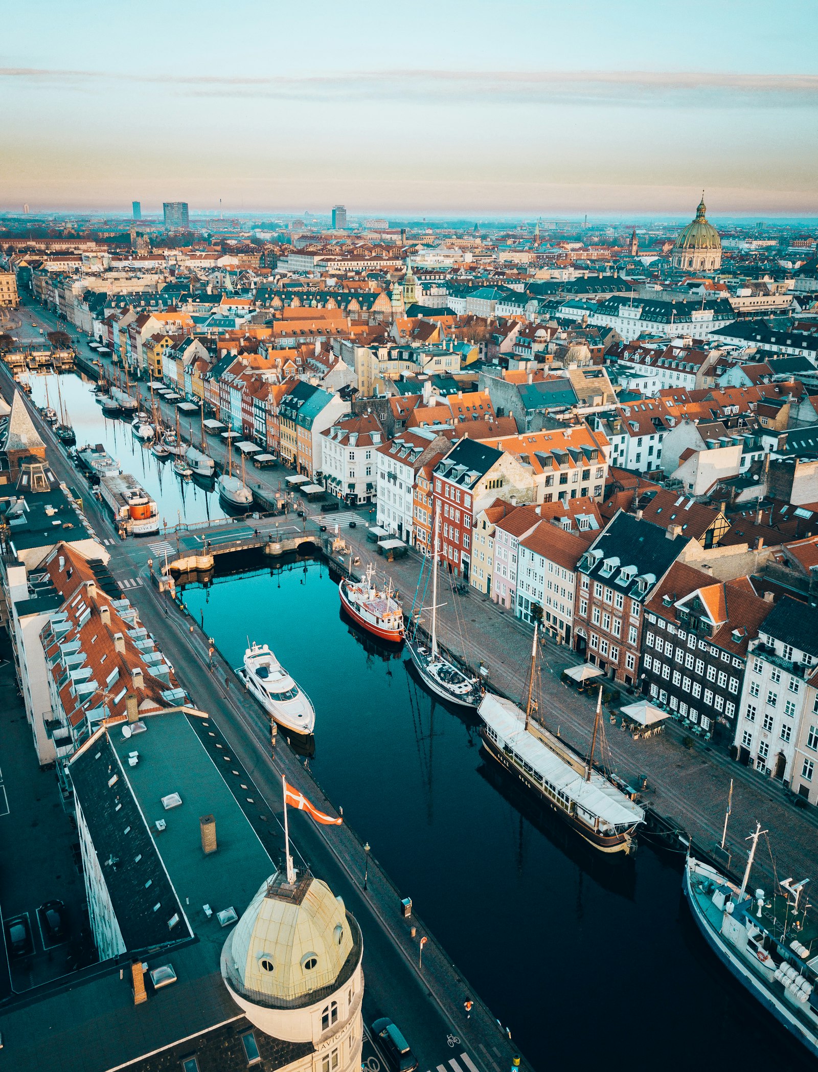 Nyhavn and the city's spires from above at first light, the Marble Church dome on the horizon. Photo by Rolands Varsbergs on Unsplash.