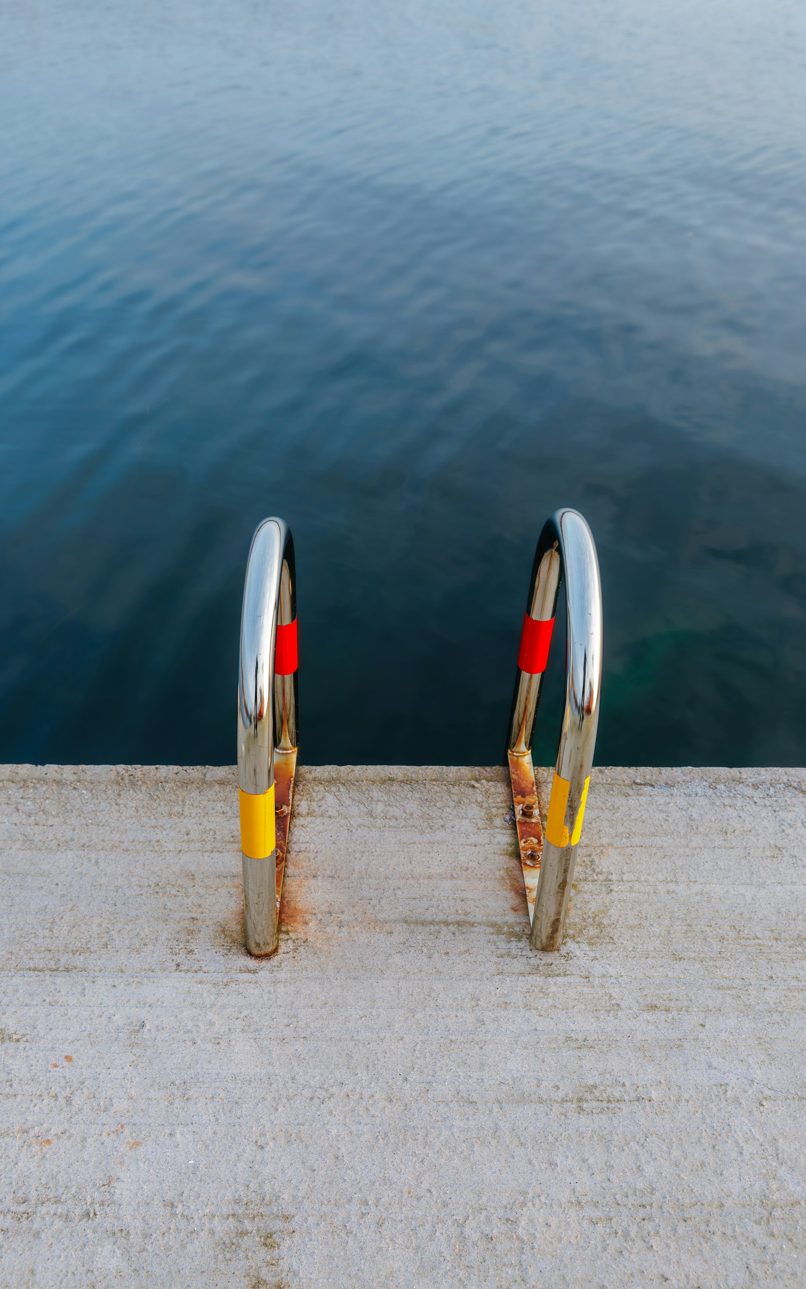 A swim ladder into the clear harbor water. Photo by heino eisner on Unsplash.