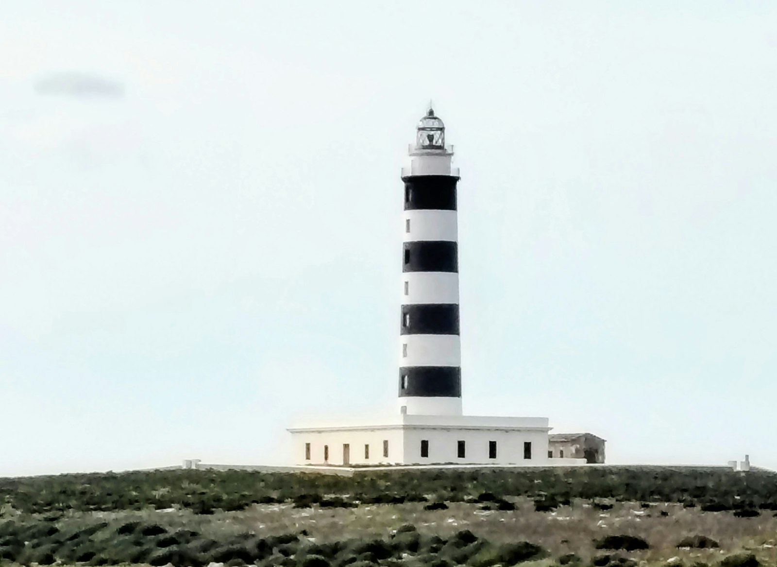 A black-and-white striped lighthouse on a barren Menorcan headland. Photo by Christine Ellsay on Unsplash.