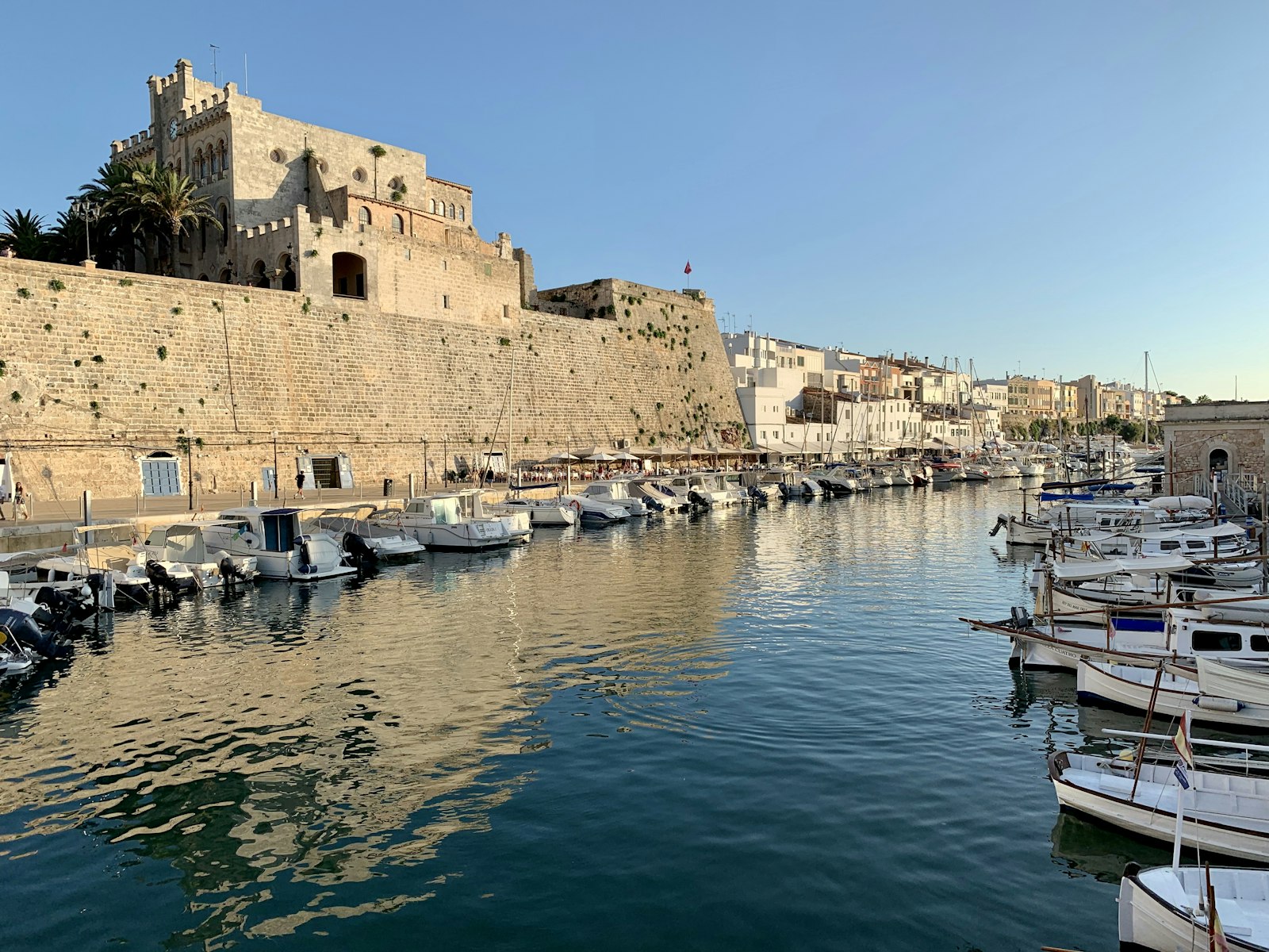 Ciutadella's old stone harbour glowing at golden hour. Photo by Alberto Almajano on Unsplash.