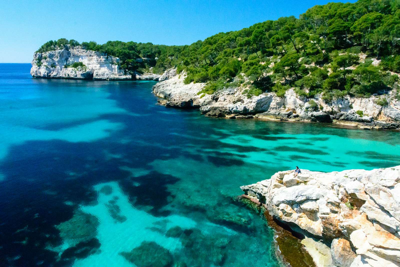 Bright turquoise water lapping the rocks of a south-coast cala. Photo by ricardo frantz on Unsplash.