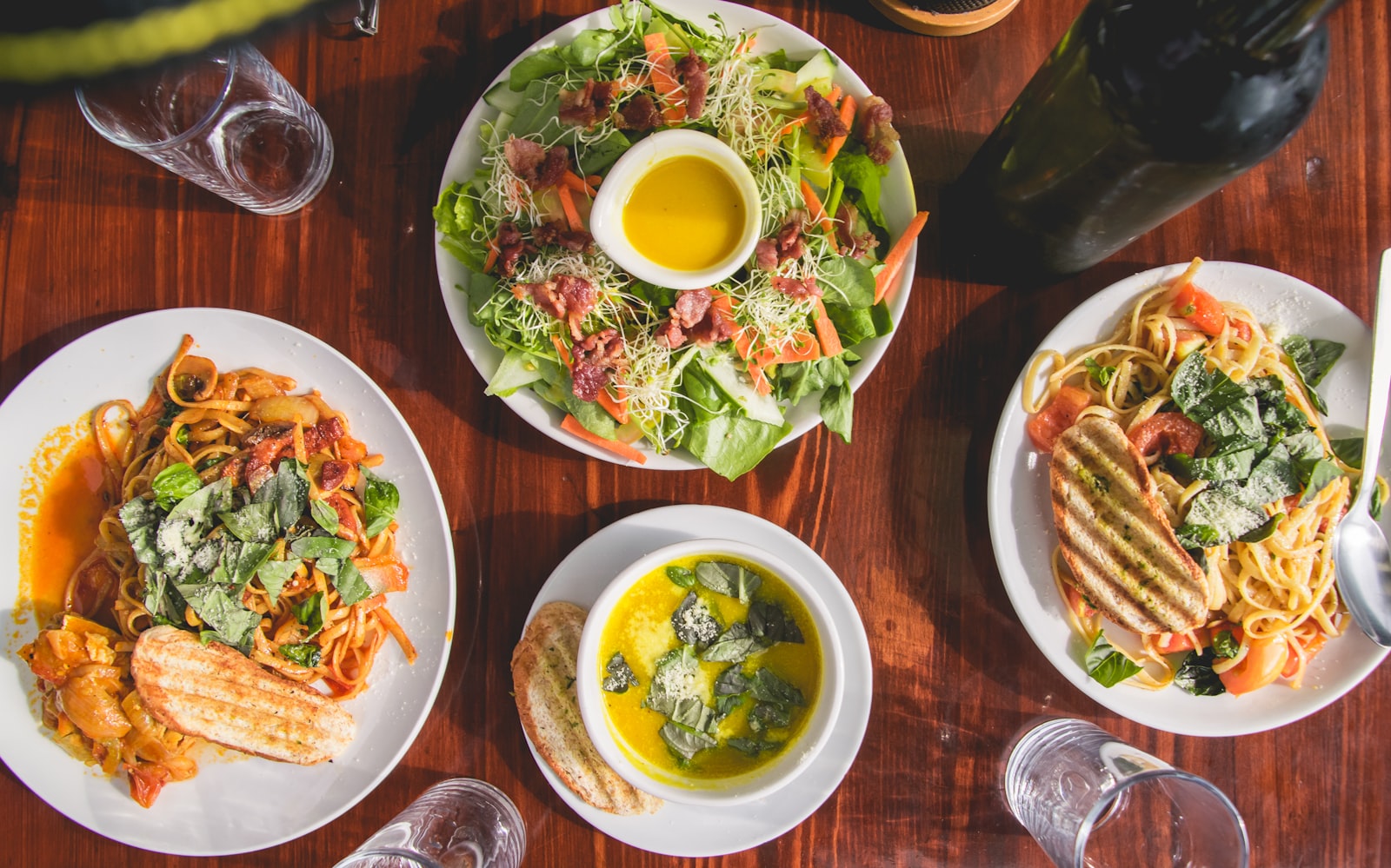 An overhead spread of colorful pasta dishes on a table. Photo by Vernon Raineil Cenzon on Unsplash.