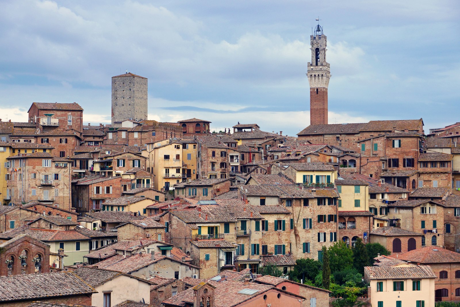 Siena's brick rooftops and the Torre del Mangia rising over the medieval city. Photo by Martti Salmi on Unsplash.