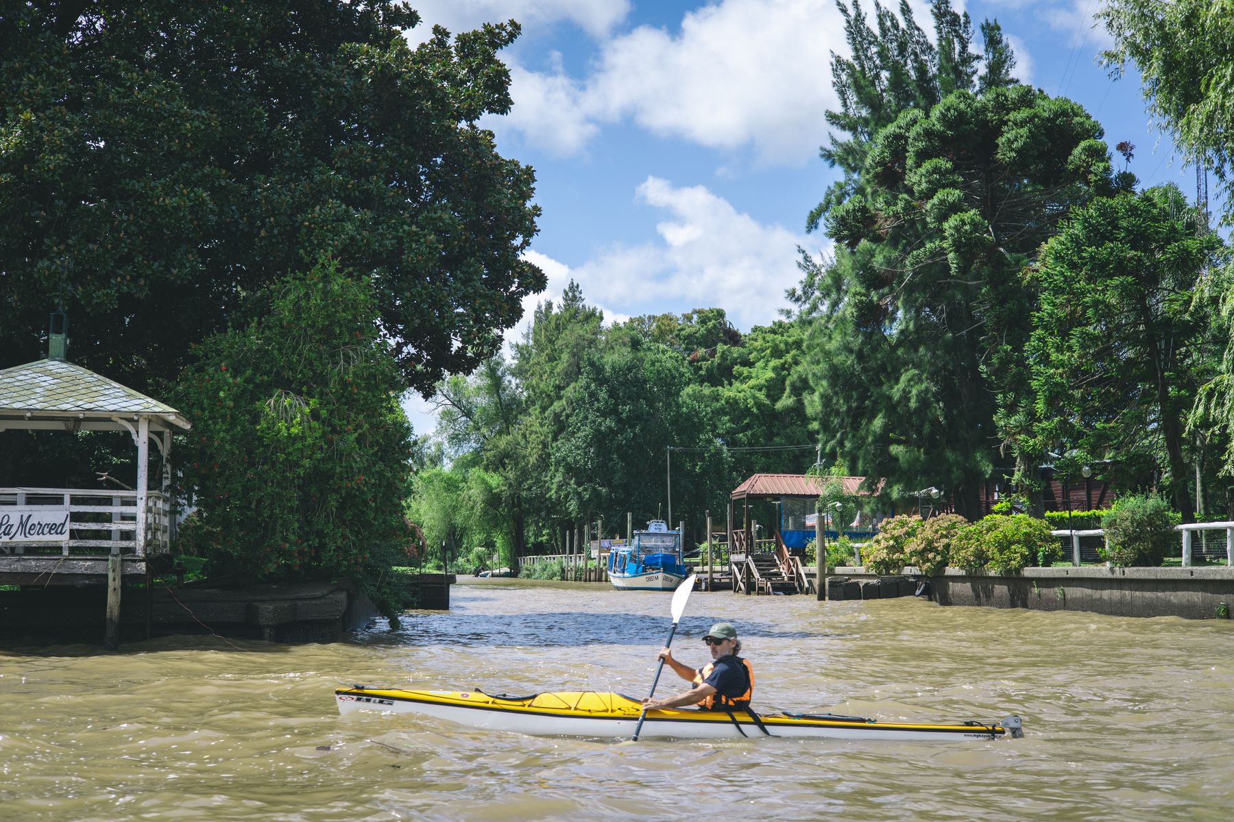 A kayaker gliding down a leafy green channel of the Tigre delta. Photo by Rafael Rodrigues on Pexels.