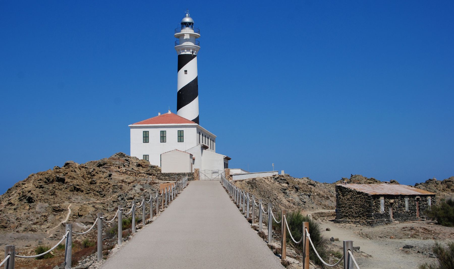 El faro de Favàritx, de franjas helicoidales en blanco y negro, sobre su cabo rocoso de Menorca. Foto de Tom D'Arby en Pexels.