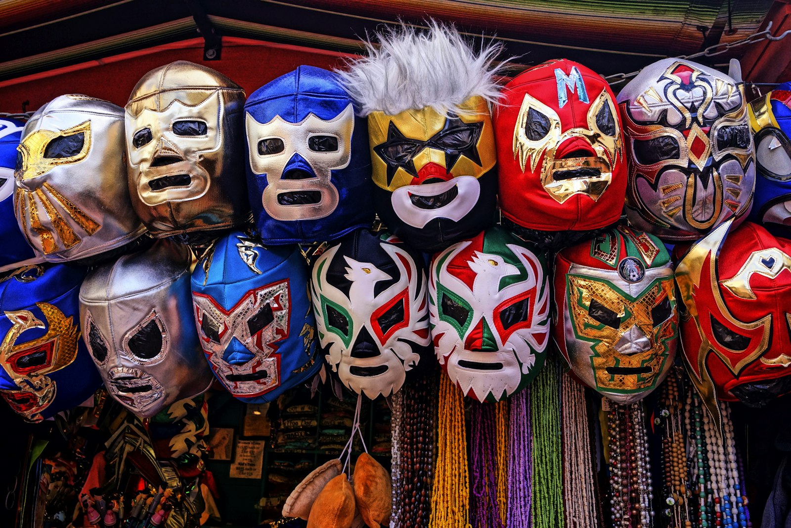 Rows of colorful lucha libre masks for sale on a vendor's stand. Photo by Larry Costales on Unsplash.