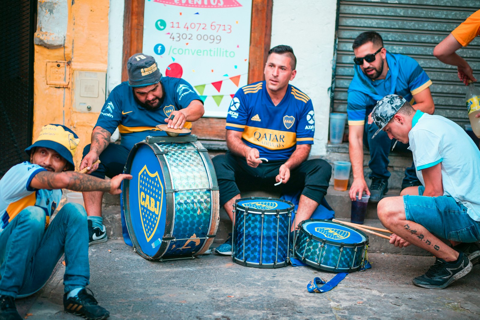 Hinchas de fútbol con camisetas azul y oro y sus bombos en una calle de Buenos Aires. Foto de Barbara Zandoval en Unsplash.