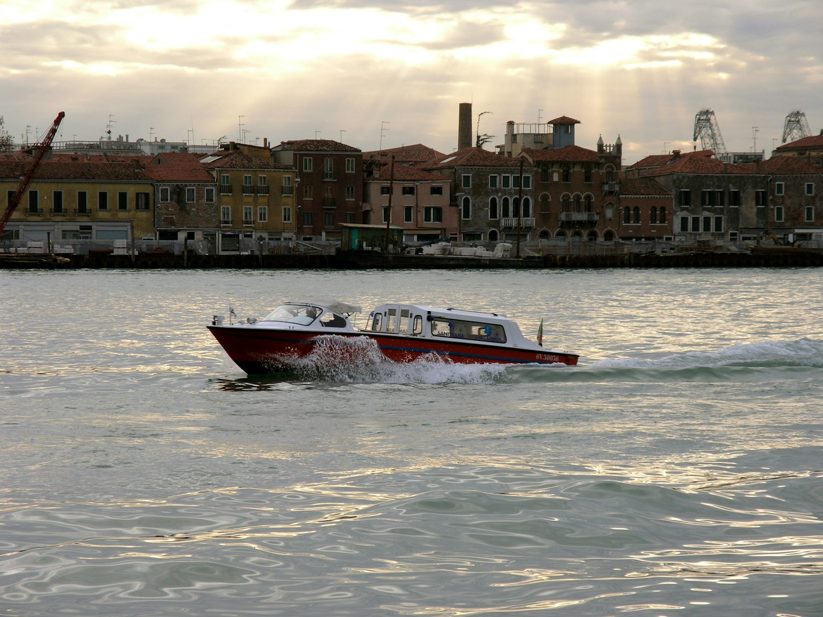 A polished wooden water taxi crosses the Venetian lagoon at golden hour. Photo by Thomas Vogel on Unsplash.