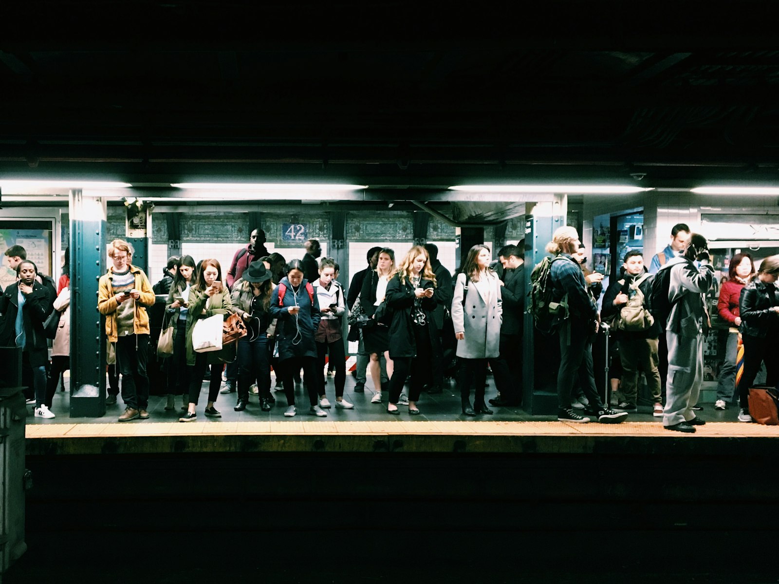 Una multitud de pasajeros esperando hombro con hombro en un andén del metro de Nueva York. Foto de Eddi Aguirre en Unsplash.