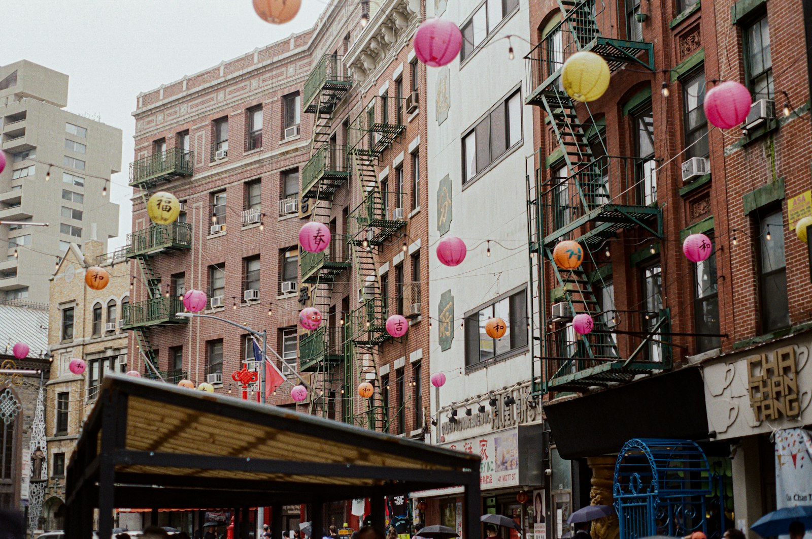 Farolillos de papel cruzando una calle de Chinatown en Nueva York, con las escaleras de incendios trepando por el ladrillo. Foto de Ruben Abreu en Unsplash.