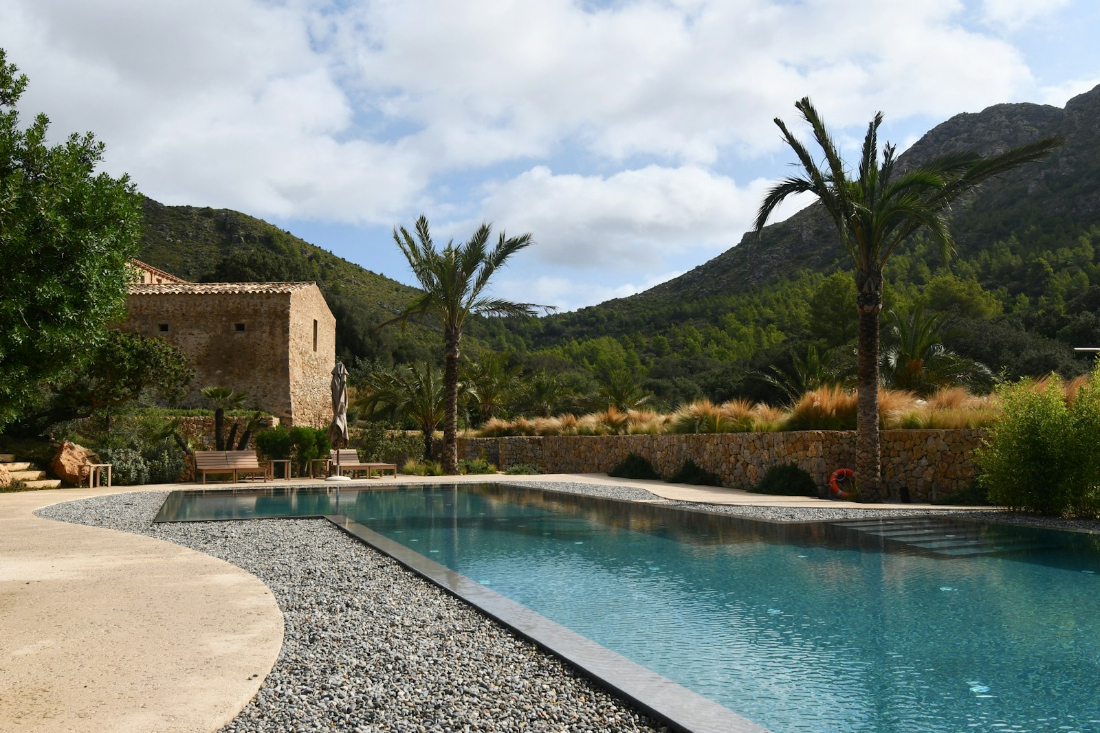 A stone farmhouse with a pool and terrace against green hills, the kind of villa a group rents on Menorca. Photo by Max Harlynking on Unsplash.