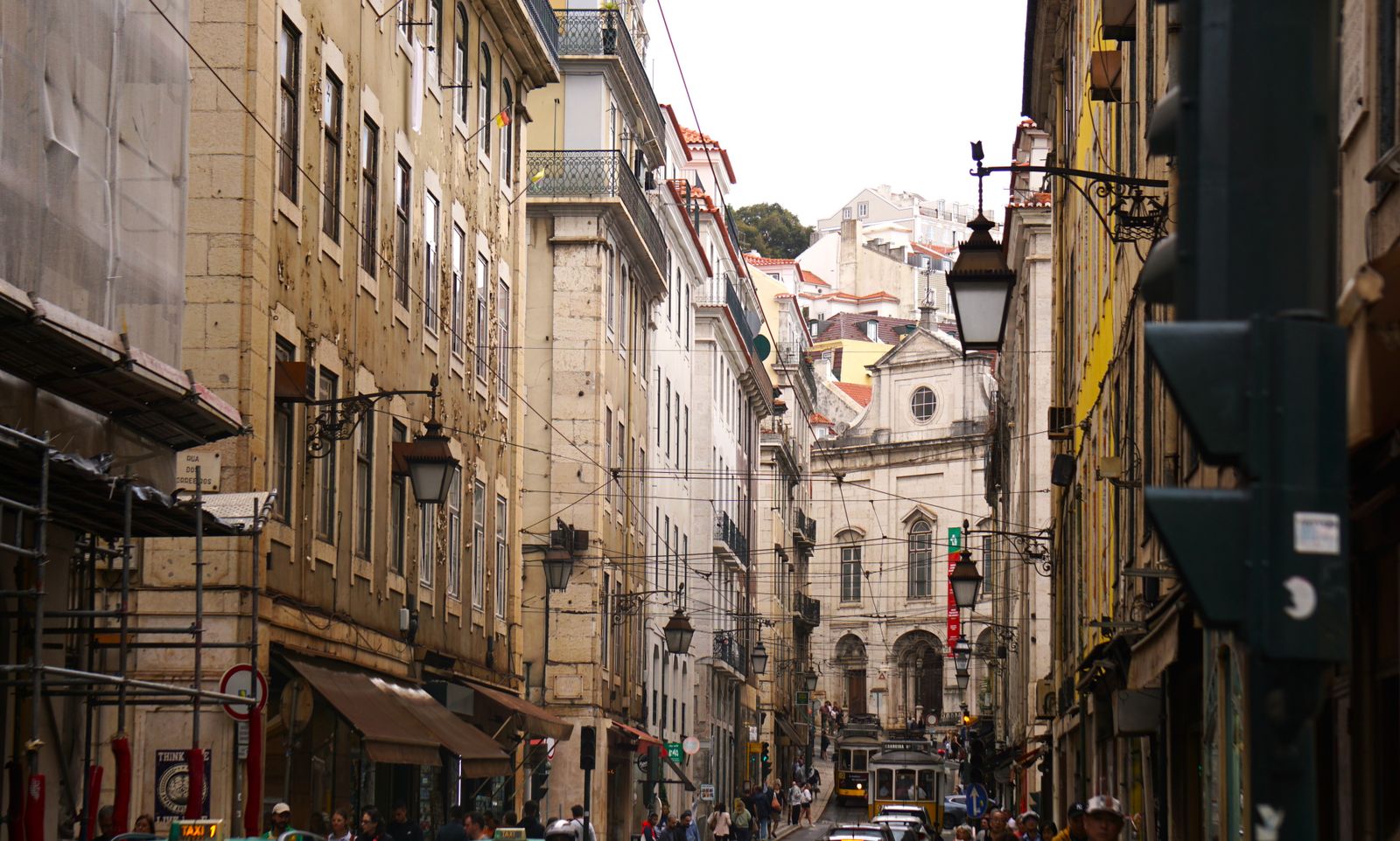 A steep Lisbon street of pastel facades dropping towards the Baixa. Photo by Emma on Pexels.