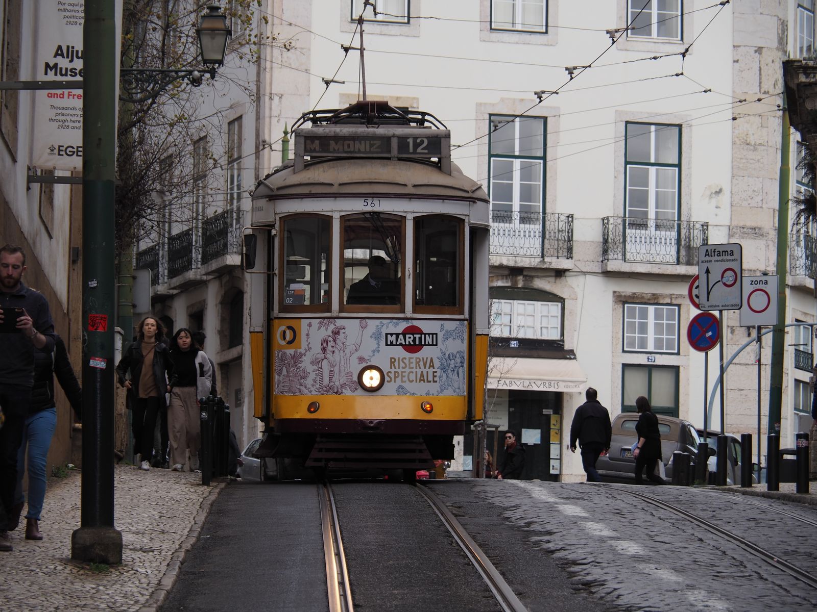 A yellow Lisbon tram on its tracks between the buildings of the old city. Photo by Theo Felten on Pexels.