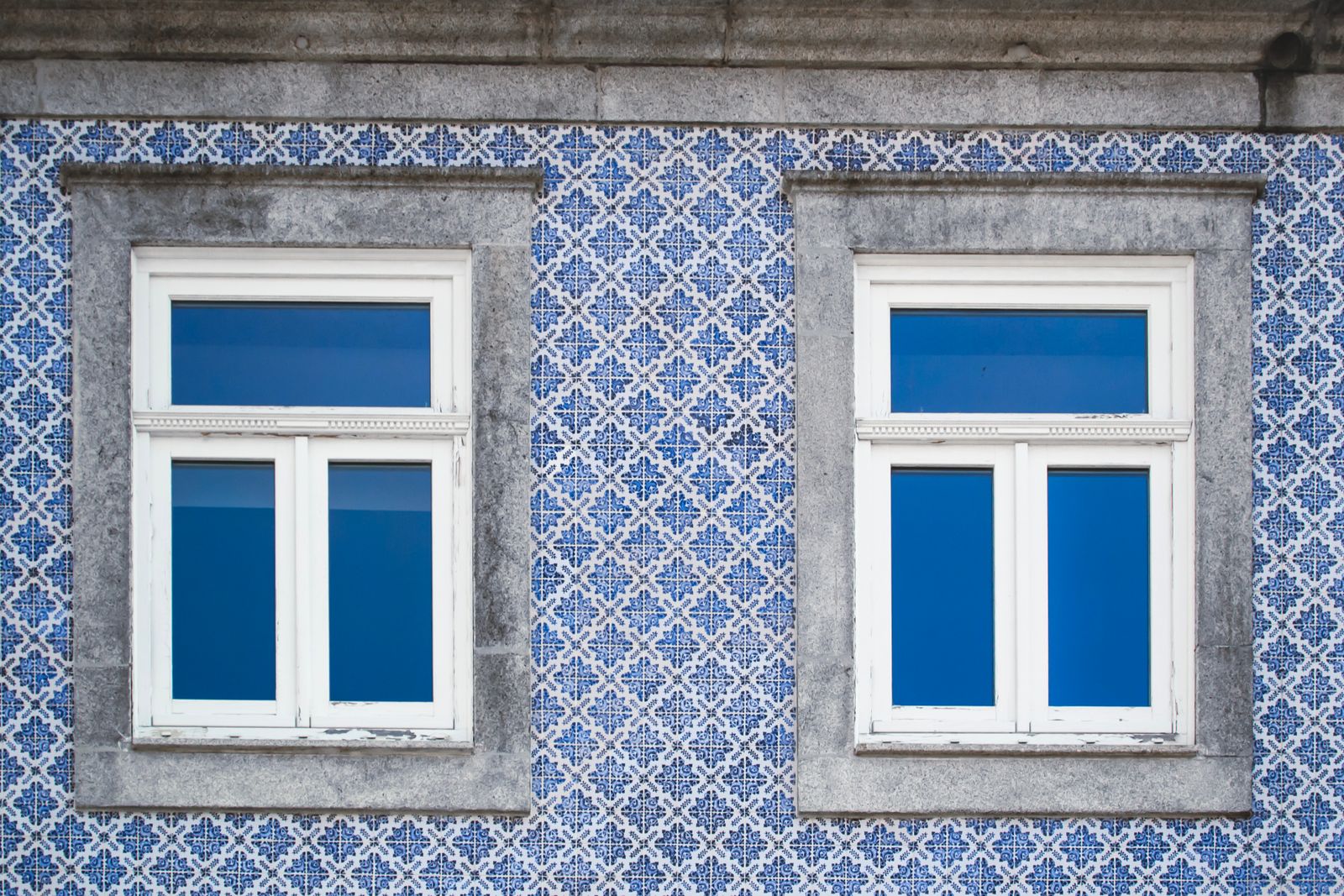 A Lisbon facade covered in blue-and-white azulejo tiles around two windows. Photo by Sandra Mosconi on Pexels.