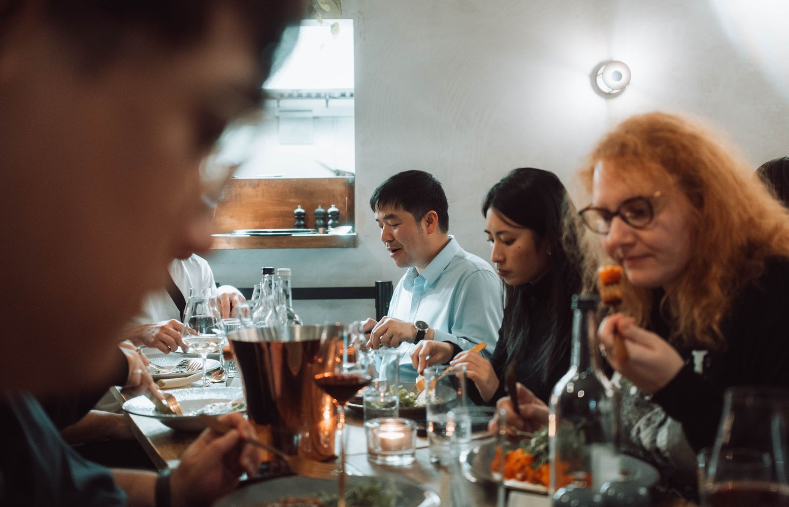 A group of friends sharing a long table over dinner. Photo by Viridiana Rivera on Pexels.