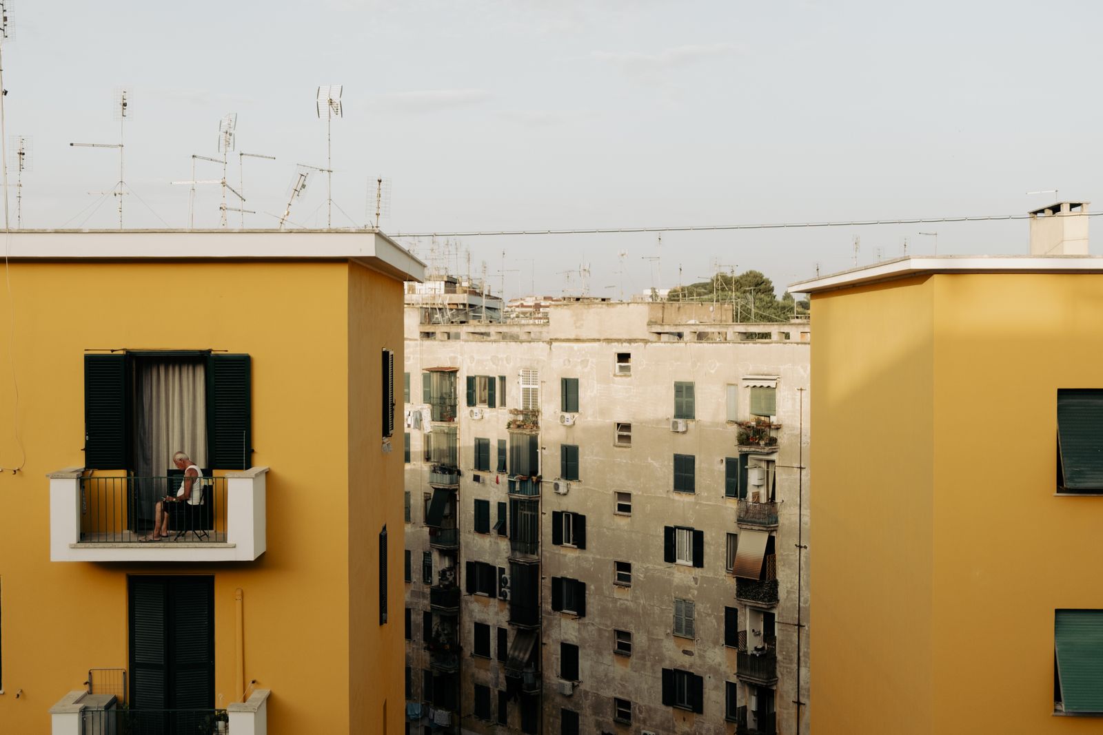 A person on the balcony of an old apartment building on a European street. Photo by Matteo Basile on Pexels.