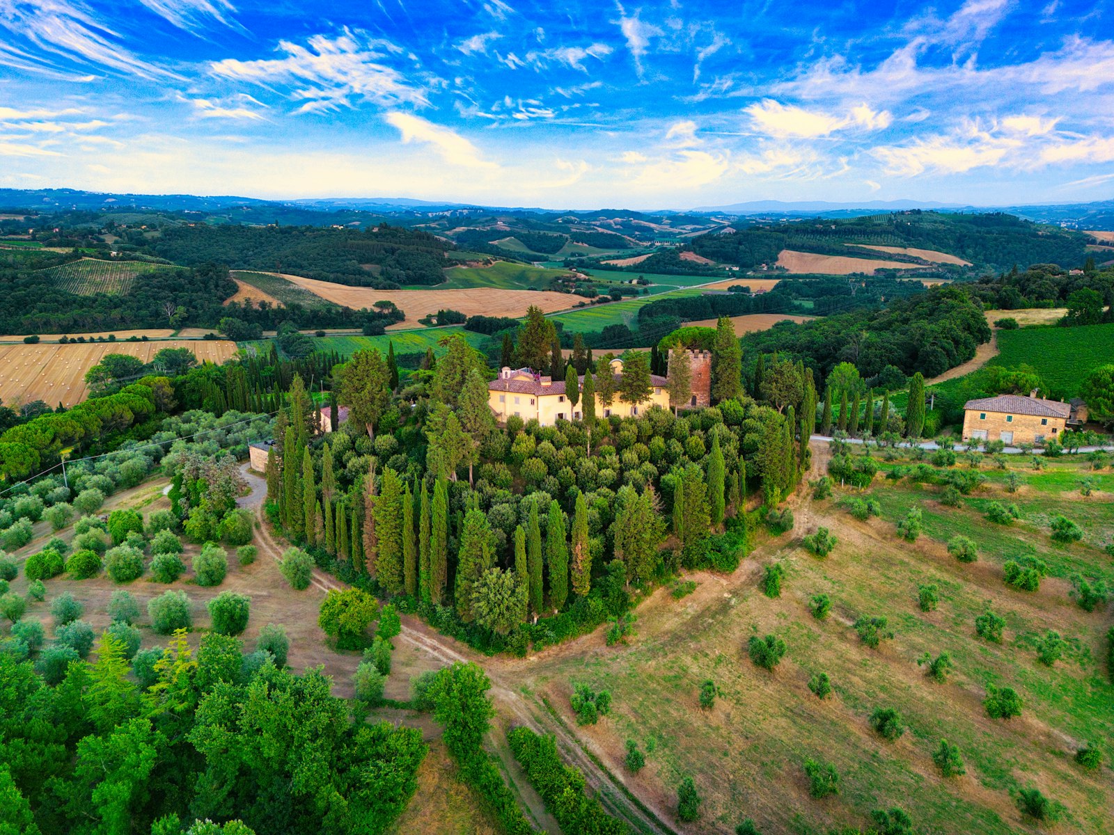 A Tuscan farmhouse ringed by cypress and olive groves in the hills just outside Siena. Photo by Simon Barber on Unsplash.
